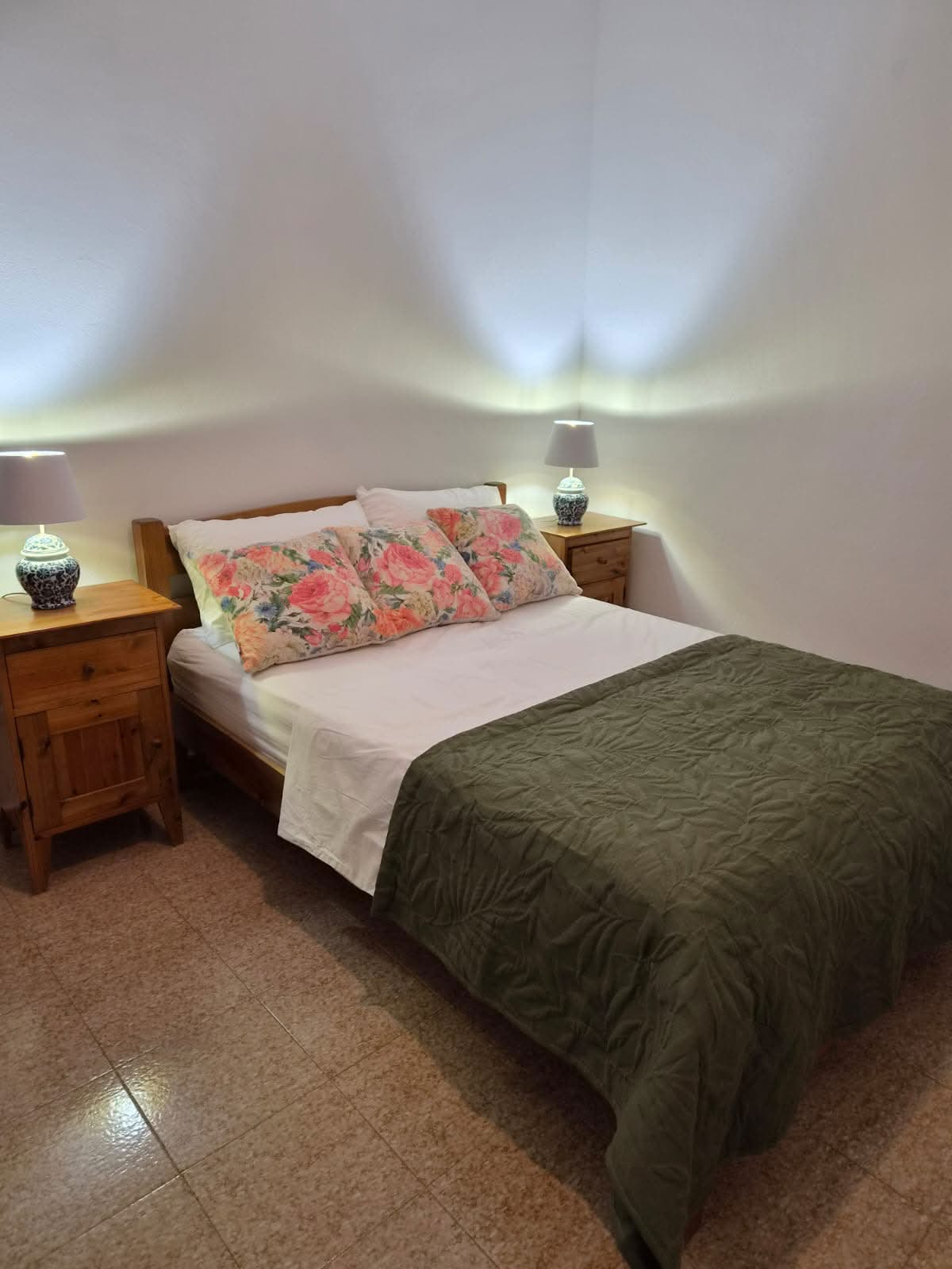Drewniana szafka nocna z porcelanową lampą — ciepły, domowy detal.