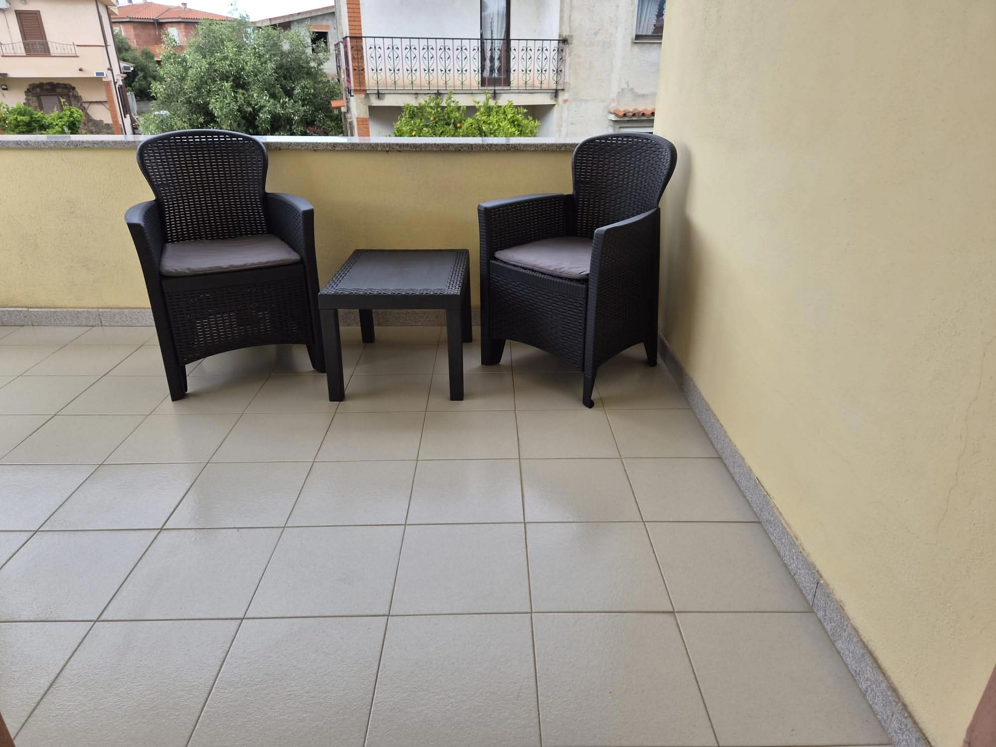 Zaciszny balkon z fotelami — widok na ogrody sąsiadów, cisza i śpiew ptaków.